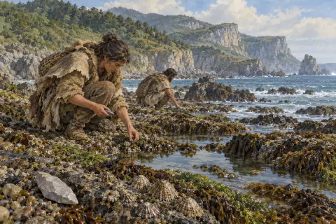 Dos personas recogiendo moluscos entre las rocas del litoral cantábrico.
