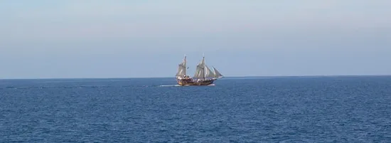 Barco de vela en alta mar sobre el inmeso cielo azul